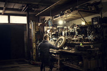 Mechanic repairing vintage motorcycle wheel at workshop bench