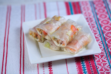 Spring roll with seafood on a white plate on a light background