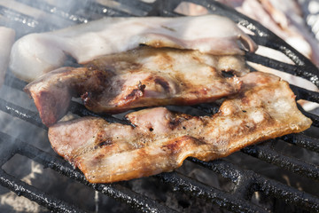 Grilling bacon, pork chop with delicious toasted traces. Smoke. Close up view