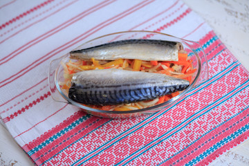 Fish a mackerel with stewed vegetables in a glass plate on a light napkin