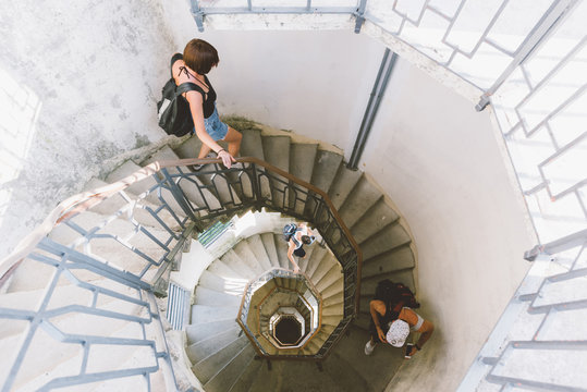 High angle view of three young adults moving down spiral staircase, Como, Lombardy, Italy
