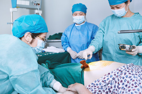Surgeons swabbing patient abdomen in maternity ward operating theatre