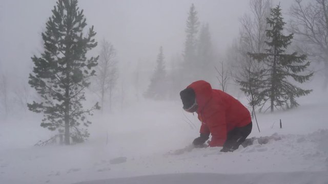 A man shoveling snow during a storm in the Swedish mountains