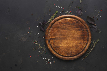 Round wooden plate on dark wooden background top view