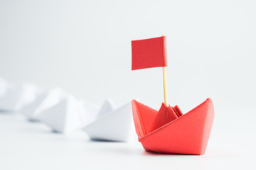 Leadership concept with red paper ship leading among white