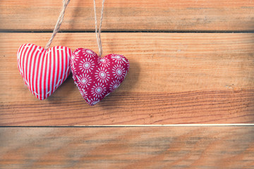 Two red fabric hearts on old wood background