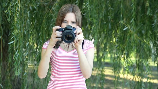 Woman amateur photographer adjusts specular professional camera