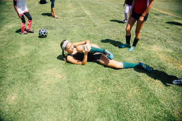 Schoolgirl soccer player lying injured on school sports field