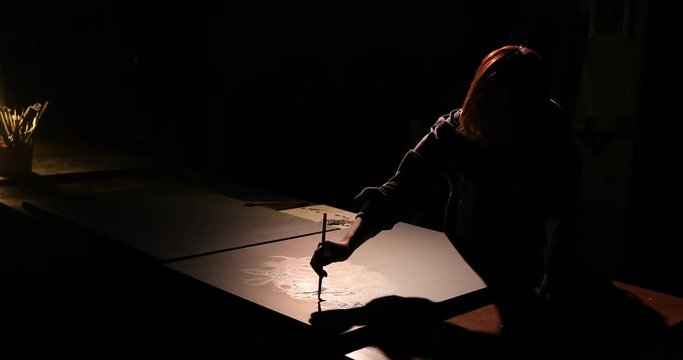 Female artist painting with paintbrush in the dark