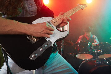 Obraz premium The rock band performs on stage. The guitarist is in the foreground.