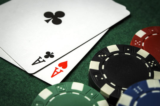 A pair of aces on the table with a pile of poker chips