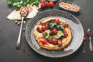 Hummus with vegetables and seafood on black background