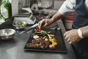 Chef cooking juicy beef steak at restaurant kitchen