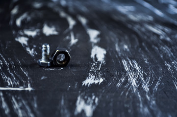Nuts for repairs lying on a wooden table. Iron nuts and screws f