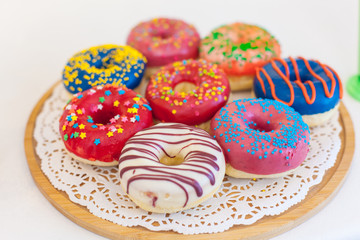 Picture of assorted donuts in a box with chocolate frosted, pink glazed and sprinkles donuts