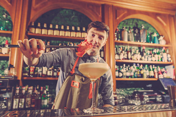 Expert barman is making cocktail at night club.