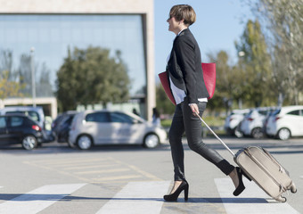 Fototapeta premium Businesswoman with trolley bag walking in urban environment