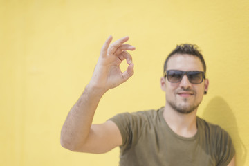 young man showing okay gesture wearing sunglasses