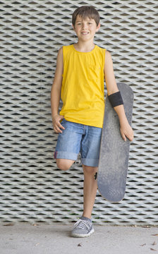 A teenage boy carrying skateboard and smiling