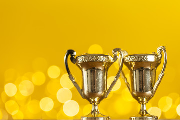 Gold award trophy against bright yellow background with blurred lights