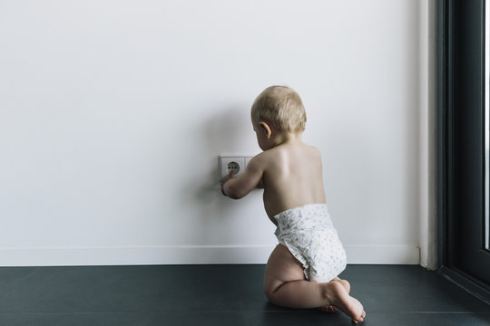 Baby touching unsecured power outlet