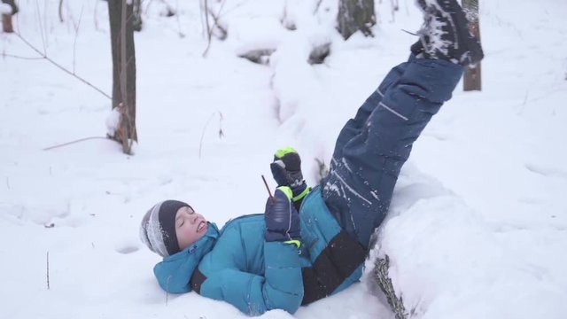 Child falls into the snow in slow motion. Active sports outdoors. Winter Sunny day