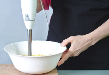 Mujer haciendo un postre casero con batidora