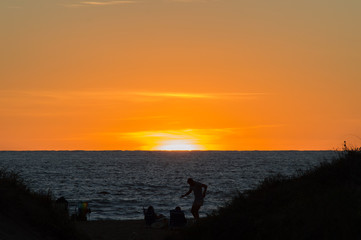 Fototapeta premium silhouettes on the beach watching the sunset in Punta del Este, Uruguay