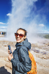 woman photographing eruption of Strokkur Geyser in Iceland