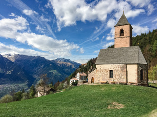 Berge, Wiese, blauer Himmel und Kirche in Hafling, Südtirol