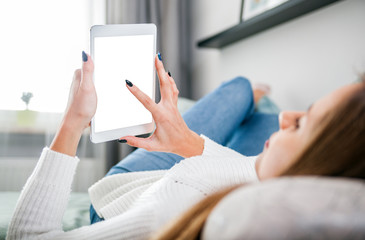 Woman on sofa at home using tablet computer and relaxing