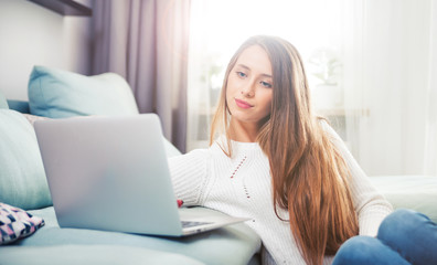 Woman at home using laptop computer on sofa and resting