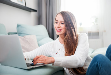 Obraz premium Woman at home using laptop computer on sofa and resting