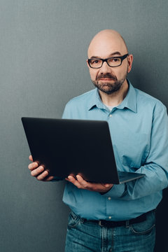 Bald man in glasses with laptop computer
