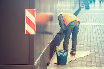 worker painting a wall on the street, copy space available on the left