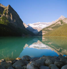 Reflection on Lake Louise in Rocky Mountains in Canada during sunrise on sunny day - 187618097