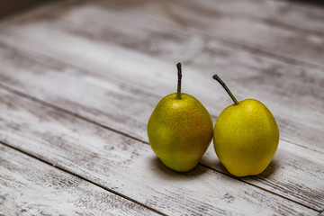 ripe yellow and green pears on a napkin on a wooden white background.
