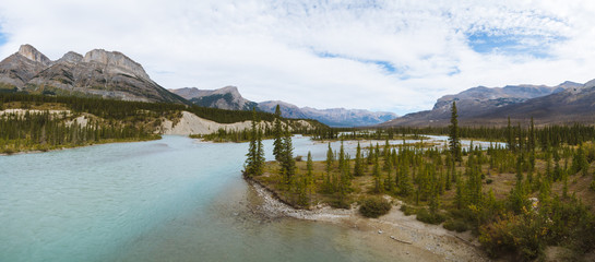 Panorama of scenic remote wide valley with river and forest in Rocky Mountains in Canada on cloudy day