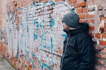 Man waiting against a graffiti covered wall