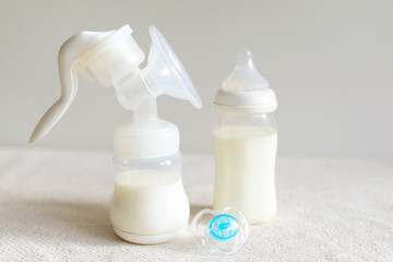 Breast pump, bottle with milk and nipple for baby.