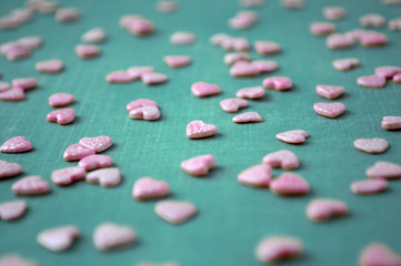 Obraz na płótnie Canvas Valentine's day background. Pink confectionery sprinkling In the form of hearts on blue background. Picture for a menu or a confectionery catalog.