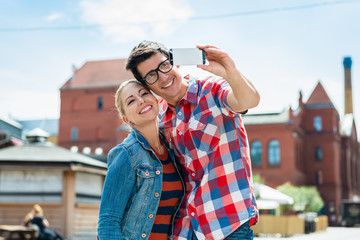 Tourist couple, woman and man, taking holiday selfie on rooftop in Berlin