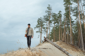 Mobile generation. Hipster young man with backpack looking in side. View tourist traveler on background sky. Mock up for text message. Male hands using smartphone, holding gadget