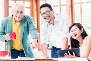 Cheerful professional team looking at camera while working together on an innovative project