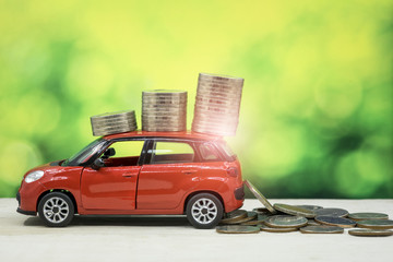 Car make income concept, Red car have many coin on roof, Car Loan and green bokeh background