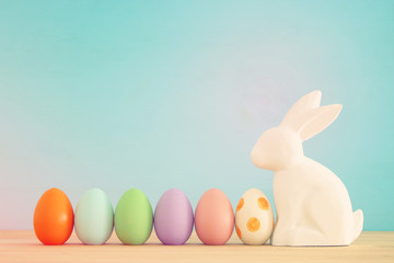 Cute bunny next to easter colorful eggs over colorful background.