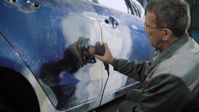 Car mechanic sanding car