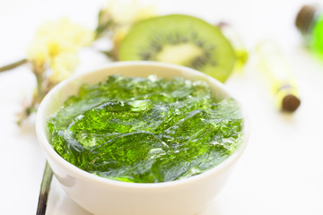Natural green cosmetics concept. A container of jelly cream soap and kiwi, white background, top view
