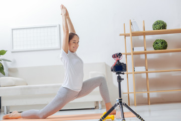 Yoga teacher. Cheerful enthusiastic young blogger standing in a popular yoga position while...