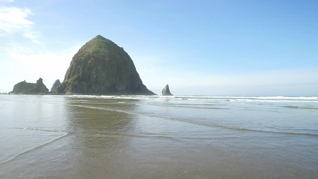 Pacific Ocean water rolls onto the beach next to Haystack Rock on the Oregon coast. ProRes file, shot in 4K UHD.